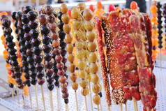 在中国绥芬河的街头, 一根棍子上的焦糖水果被出售.