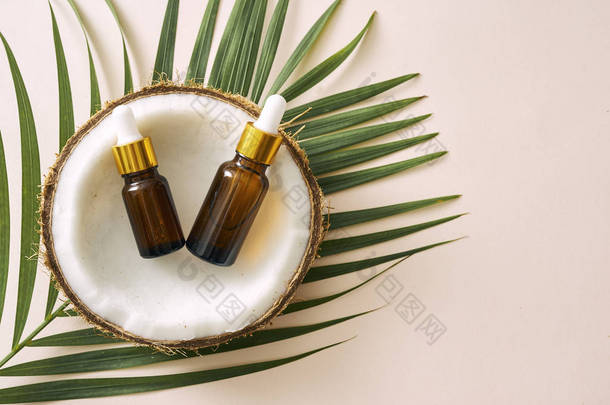 椰子油在瓶与开放坚果和纸浆在罐子, 绿色棕榈叶背景。天然化妆品.