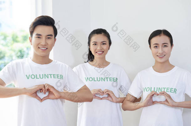 亚洲年轻人的肖像，他们是志愿者协会的成员，站在他们手中做一个心脏的形状