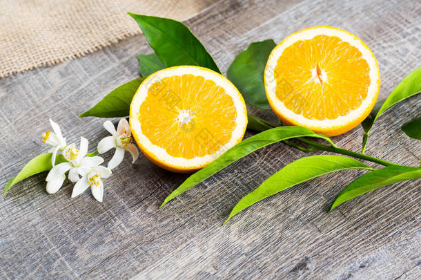 多汁的橙切成两部分和内罗利，橙树的花朵，在质朴的木材背景。橙花是柑橘的芬芳花用于香水和茶，<strong>壮阳</strong>药.