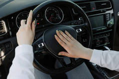 一个女人的特写是双手拿着汽车的方向盘，按喇叭.