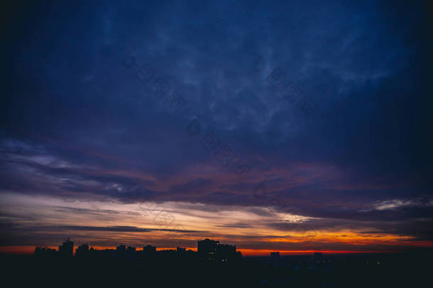 城市景观与生动的温暖的黎明。惊人的戏剧性的蓝紫色多云的天空在城市<strong>建筑</strong>的黑暗<strong>剪影</strong>之上。橙色的阳光。阴天日出大气<strong>背景</strong>。复制空间.