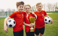 快乐运动足球队球员拿着奖杯。青少年足球锦标赛优胜者