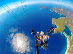滑翔伞在天空中。滑翔伞在阳光明媚的日子里，与蓝色的海水和山脉一起飞越大海。土耳其奥卢德尼兹滑翔伞和蓝色泻湖的鸟瞰图.