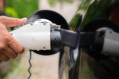 在绿色环境背景下，将充电器插头插入电动汽车。新能源汽车，内华达州正在加载电力。生态，现代汽车