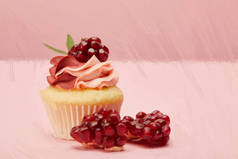画甜和美味的纸杯蛋糕与石榴种子在粉红色