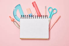 粉红色背景学校用品中空白笔记本的顶视图