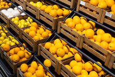 Many wooden lug boxes with brigh yellow lemons on counter