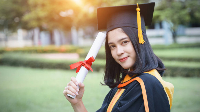 年轻的亚洲女大学毕业生在毕业典礼上获得大