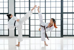 跆拳道的年轻老师和她的学生都是有着白色背景和图案的踢腿动作.