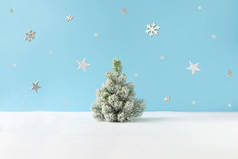 有白雪的圣诞树和明亮蓝色背景的雪花群星的创意布局。 最少的冬季自然假期场景.