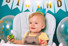 可爱的小男孩坐在椅子上，用彩色的砖头玩耍。生日，英俊的幼儿，长着大眼睛的肖像。有趣的孩子.