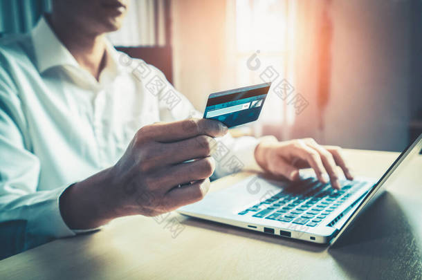 年轻人在笔记本电脑应用程序或网站上使用信用卡在网上购物。电子商务和网上购物概念.