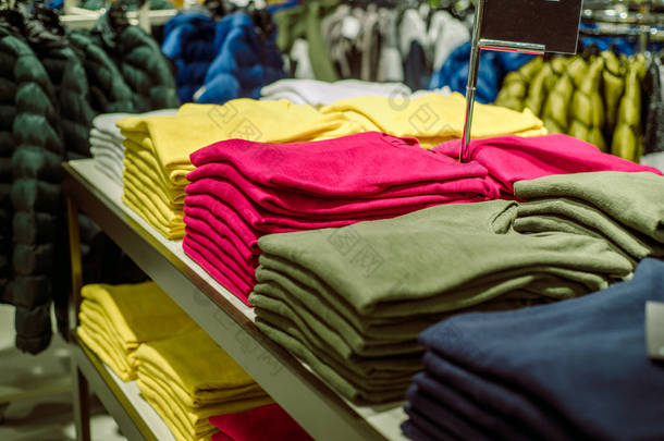 商店里有汗衫，一堆堆叠好的针织品。黄色的绿色和紫色夹克。<strong>女装</strong>堆在商店的脚后跟上.