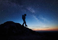 宇航员在美丽的夜空下与星星一起下山。宇航员穿着太空服探索新星球的轮廓。宇宙中的空间旅行、星系和人类的概念