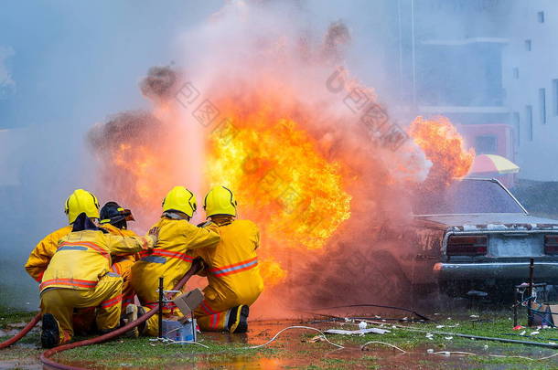 消防队员使用水和灭火器车起火，消防员使用灭火器和消防软管水，燃烧汽车气体，救援设备.