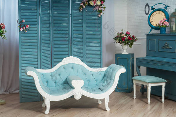 浅蓝色经典沙发的背景是客厅里的折叠式屏风.带有蓝色钢琴的经典风格的白色客厅。春季夏季室内装饰