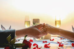 情侣们手牵着手,在日落前的餐厅里共进午餐.情人节，情侣，蜜月，晚餐，酒，浪漫的概念.