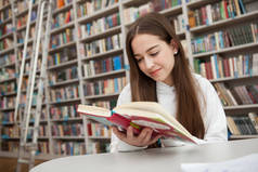 快乐的少女笑着在图书馆看书，复印空间。智力、教育观念