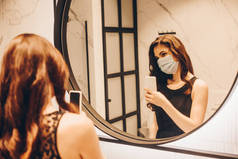 穿着黑色衣服和医疗面罩的女性在浴室拍照的选择性焦点