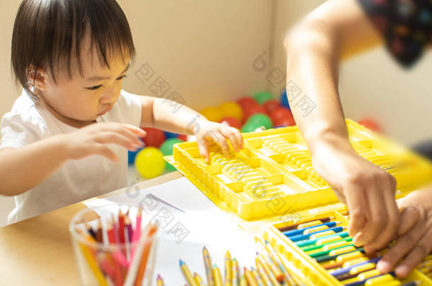 可爱的亚洲小女孩正在以完全快乐的时刻、艺术的概念和儿童教育的方式来粉刷色彩。蹒跚学步的小女孩正在练习为回家而拼搏