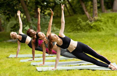 公园集体练习赛期间，吸引多种族女孩做侧板瑜伽姿势
