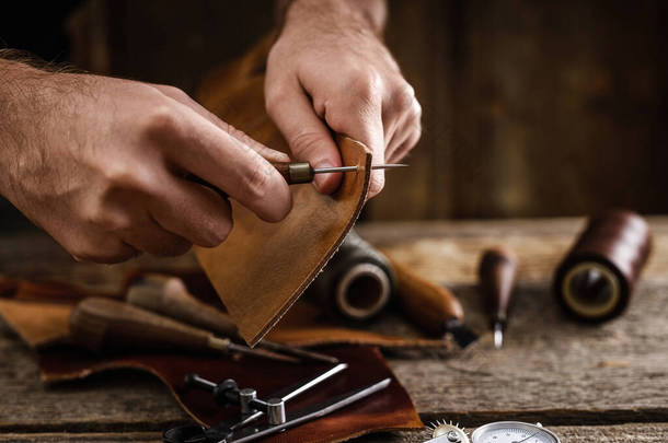 小木屋里的旧木桌上有皮革手工工具.皮革工匠的工作空间。客厅深色木<strong>质感背景</strong>.