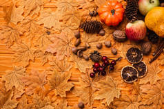 金黄色叶子上的秋季装饰和食物的顶视图，木制背景