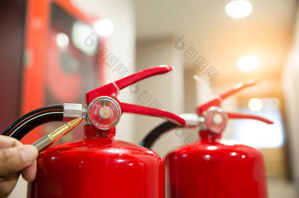<strong>消防队</strong>员正在检查大楼里的红色<strong>灭火</strong>器水箱的压力表