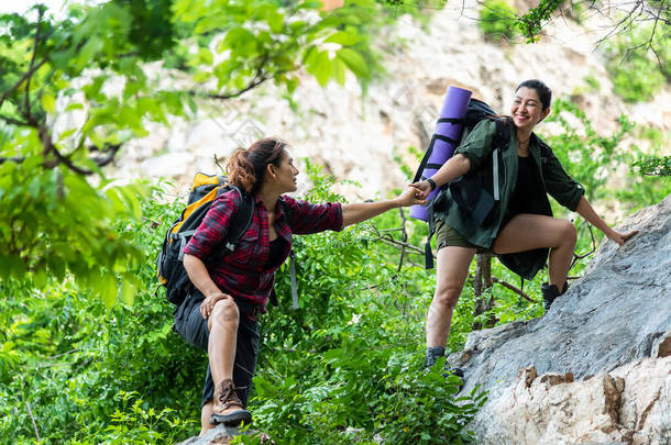 团体远足妇女帮助她的朋友爬上落山的最后一段。旅行团团队精神走在<strong>户外</strong>生活冒险和<strong>露营</strong>中.旅行概念.