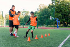 有志气的青少年足球运动员在人造足球场上进行跑步练习，克服障碍.