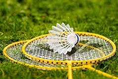 绿色草地上黄色羽毛球球拍上的白色羽毛球