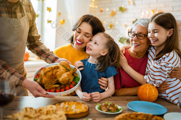 感恩节快乐！秋天的宴会。一家人坐在桌旁庆祝节日.祖父母、母亲、父亲和子女。传统的晚餐.