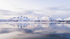 挪威海水中覆盖着覆盖着白雪的高山岩石山峰，鸟瞰着令人叹为观止的景象。冬季罗浮敦全景迷人的峡湾，宁静的自然美