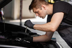 年轻的高加索汽车技师在汽车服务，检查汽车，发动机，化油器