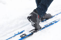 一个滑雪者的脚穿着滑雪靴在越野滑雪板上。在雪地里散步，冬季运动，健康的生活方式。特写、版权保护