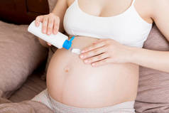 孕妇在腹部涂伸展标记霜。怀孕、人和生育的概念。孕妇在腹部涂抗张性标记霜.