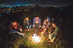五个朋友在篝火边取暖。傍晚时分