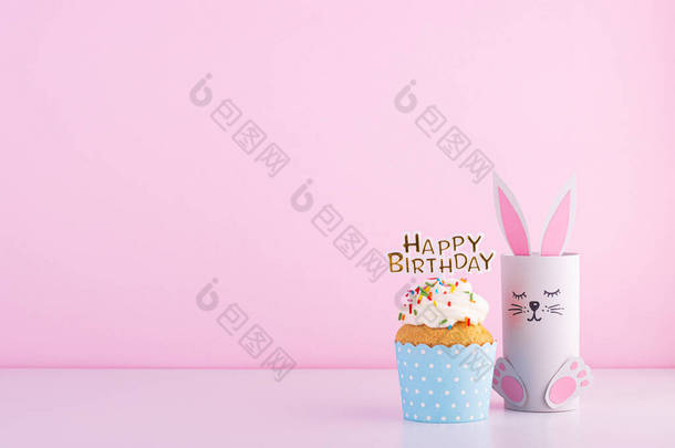 可爱的纸兔和美味美丽的蛋糕蛋糕生日粉红背景。生日宴会的背景