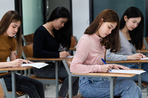 年轻的女大学生集中在课堂上做考试。3.女生们在课堂上认真地准备考试的内容.