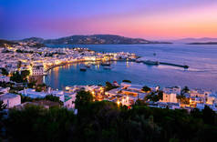 日落之后，在希腊的米科诺斯镇、 Cyclades镇、港口和港口、游轮、轮船、粉刷过的房屋上，景色多姿多彩。五彩缤纷的小镇灯火通明.