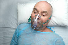 身穿蓝色衬衫的老年病人戴着面部氧气面罩，享受医疗护理、麻醉学和特别护理、氧气疗法、复苏程序等概念