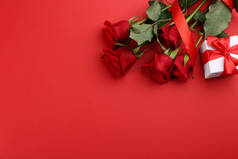 美丽的玫瑰和礼品盒在红色的背景上,平坦的放置与文字的空间.情人节庆祝活动