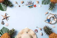 夏季水果背景设计理念.以蓝色背景为背景，带贝壳、帽子、菠萝和棕榈叶的度假海滩尽收眼底.
