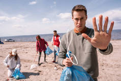 年轻男子在接近一群捡垃圾、生态概念的志愿者时表现出停下来的姿态