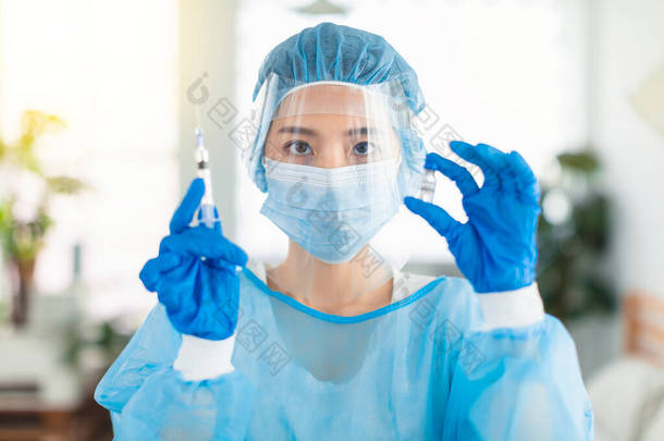医生或护士穿着长袍，戴着面具和护目镜，准备用<strong>注射</strong>器<strong>注射</strong>