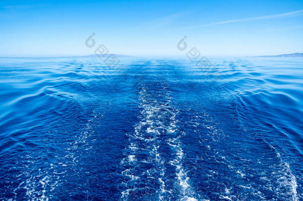 Boat wake, prop wash foam, blue calm sea and clear sky background, view from the ship. Sailing in Ae