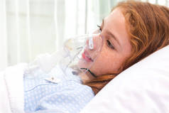 在医院里，带着氧气筒，在床上用氧气面罩吸气和治疗的可爱的亚洲小女孩。