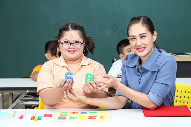 亚洲残疾儿童或者，孤独症儿童在课桌边学习阅读、写作和锻炼手部和手指肌肉。专注微笑快乐残疾儿童的概念