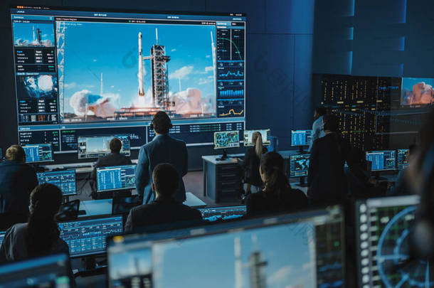 任务控制中心人员小组见证了成功的空间<strong>火箭发射</strong>。飞行管制员坐在电脑前展示及监察飞行任务。团队精神站起来观看.